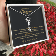 Hand holding a white jewellery box with a personalised graduation name necklace and Daughter message card beside red flowers.