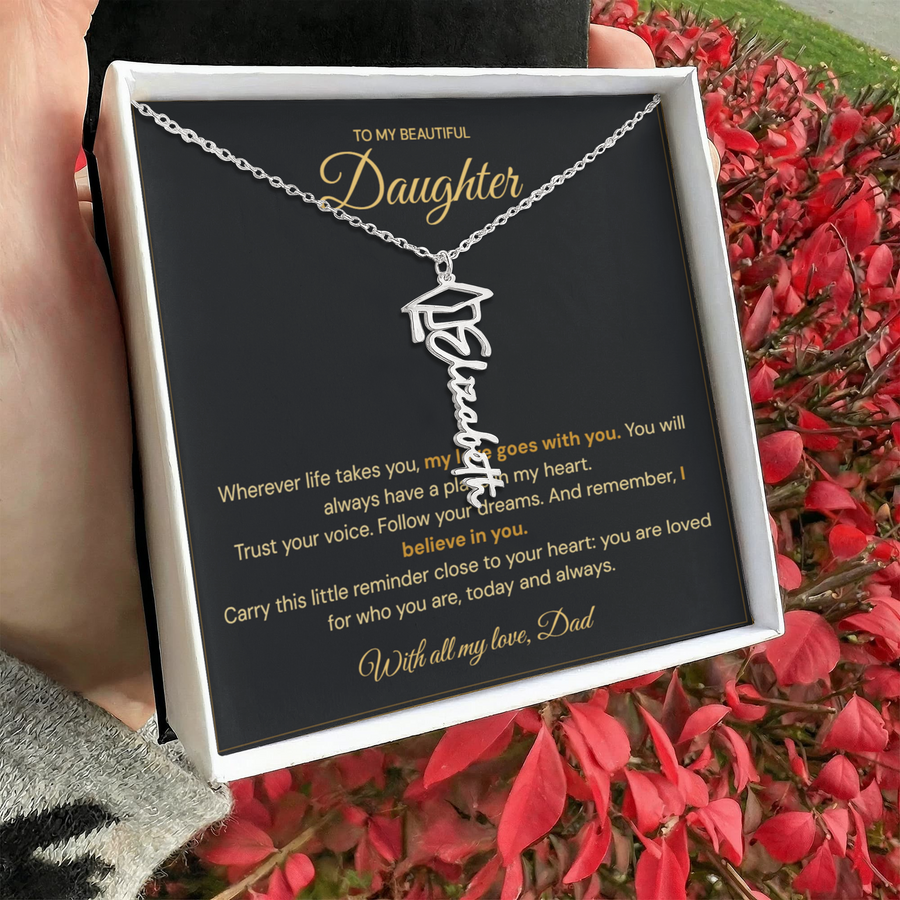 Hand holding a white jewellery box with a personalised graduation name necklace and Daughter message card beside red flowers.