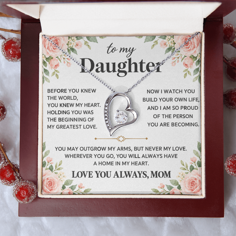 Silver-tone heart pendant necklace displayed in a red box on a festive white surface.