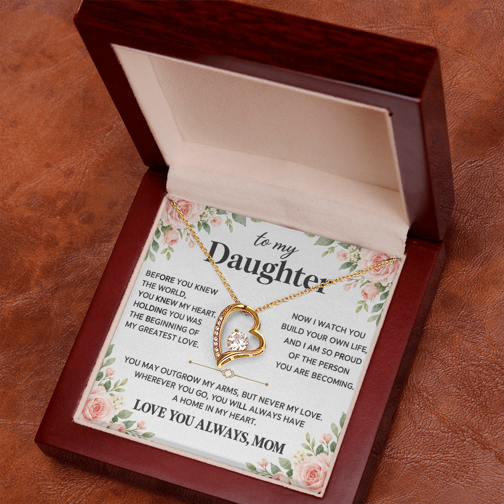 Close-up gold-tone heart pendant necklace in an open red presentation box.
