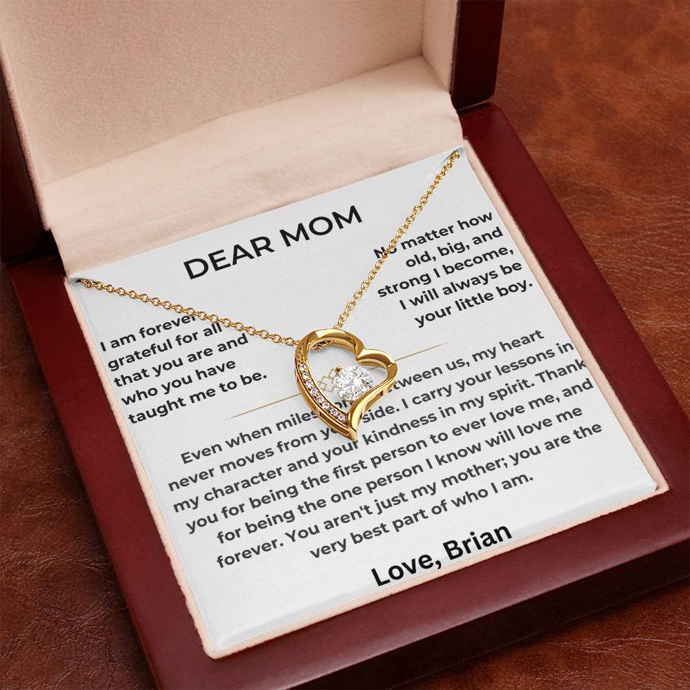 Gold heart necklace arranged on a Dear Mom message card in an open red box