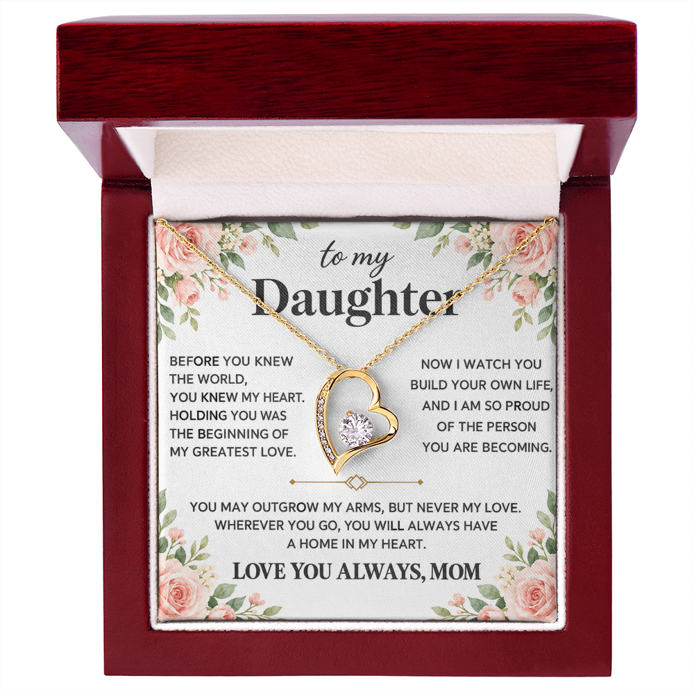 Gold-tone heart pendant necklace displayed in an open red box on a leather surface.