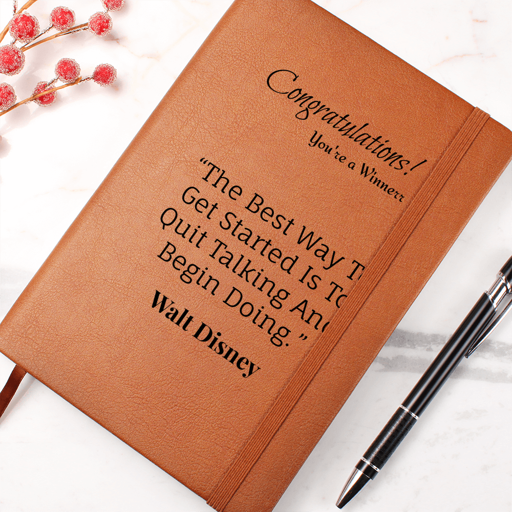 Tan journal with Walt Disney encouragement quote and elastic closure beside a black pen