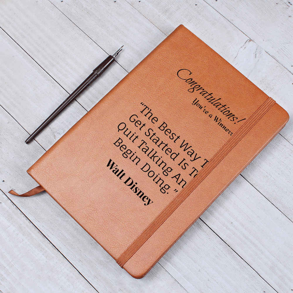 Brown journal displaying its winner message and Walt Disney quote beside a black pen