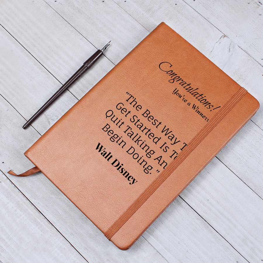 Brown journal displaying its winner message and Walt Disney quote beside a black pen