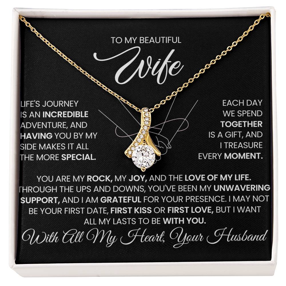 Gold-tone ribbon pendant necklace displayed on a black message card in a white box.
