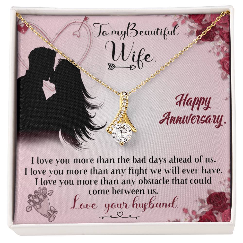 Gold-tone ribbon pendant necklace displayed on a pink anniversary message card for a wife.