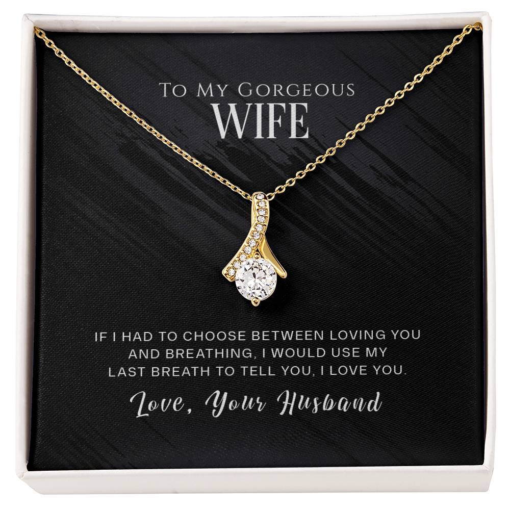 Gold-tone ribbon pendant necklace displayed on a black message card in a white box