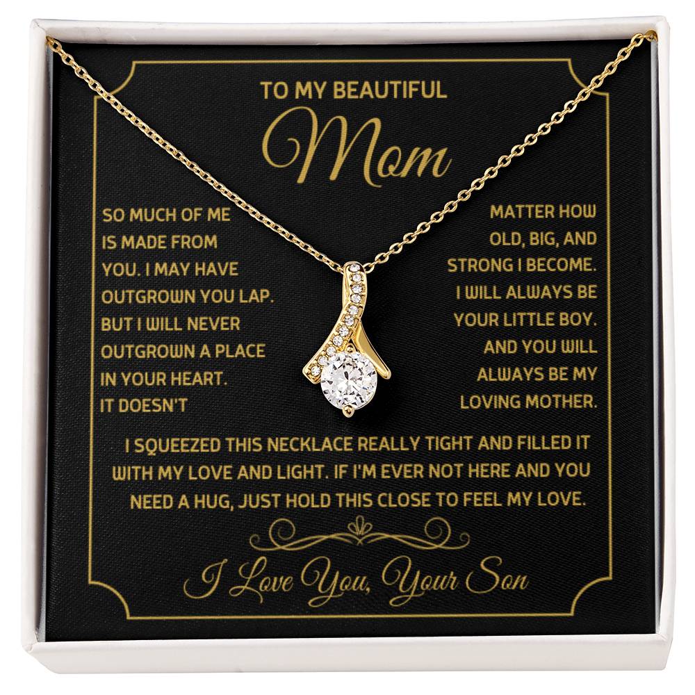 Gold ribbon pendant necklace arranged on a black message card in a white box
