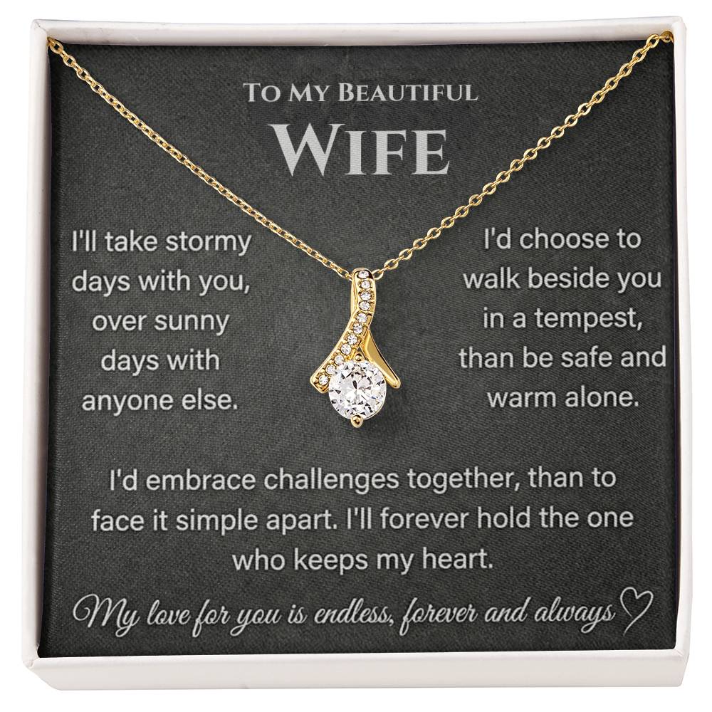 Gold-toned ribbon-shaped necklace displayed on a printed wife message card in a white-edged box.
