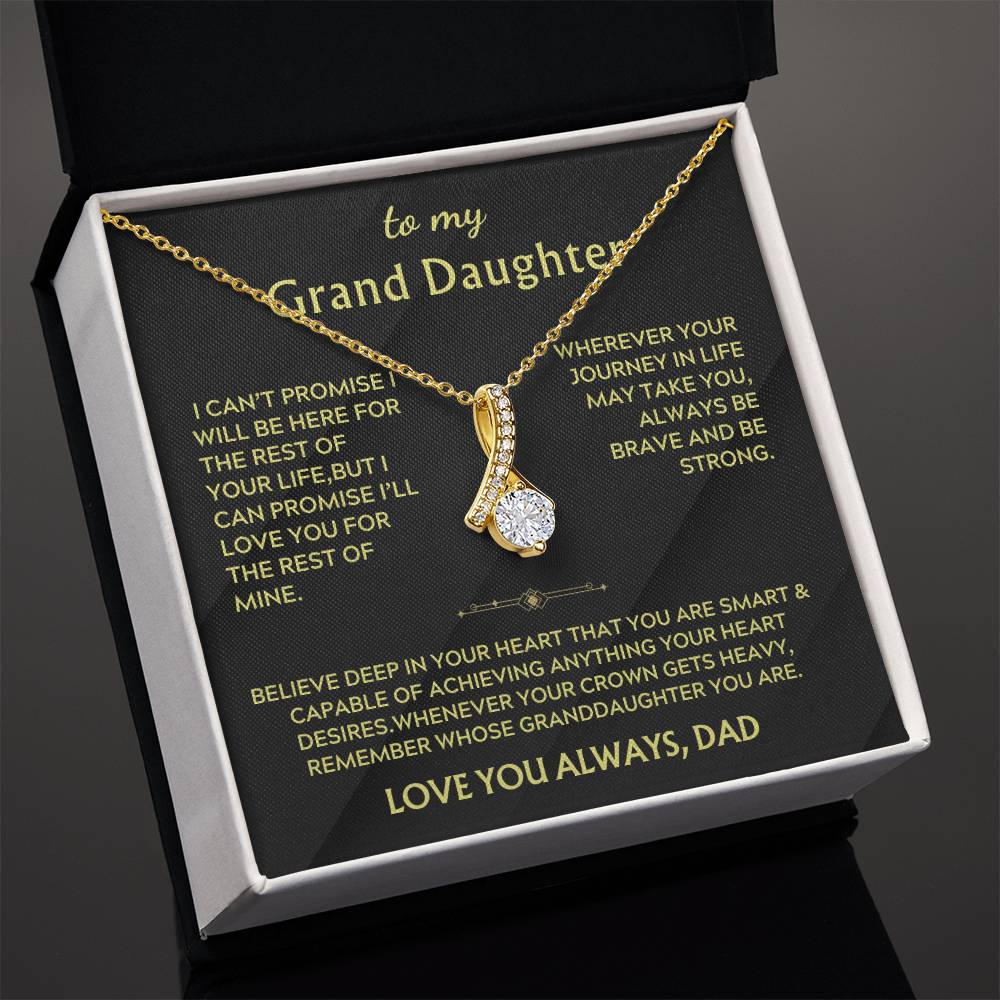 Angled view of a gold ribbon pendant necklace resting on its granddaughter message card.