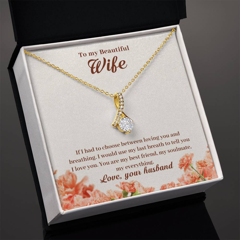 Angled open black jewellery box displaying a gold-tone pendant and wife message card.