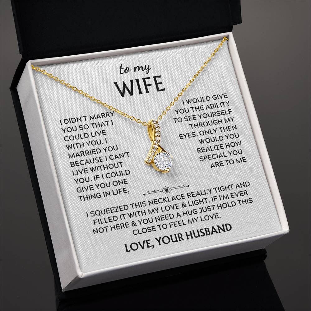 Angled view of a gold-tone ribbon pendant necklace on a wife message card in an open box.