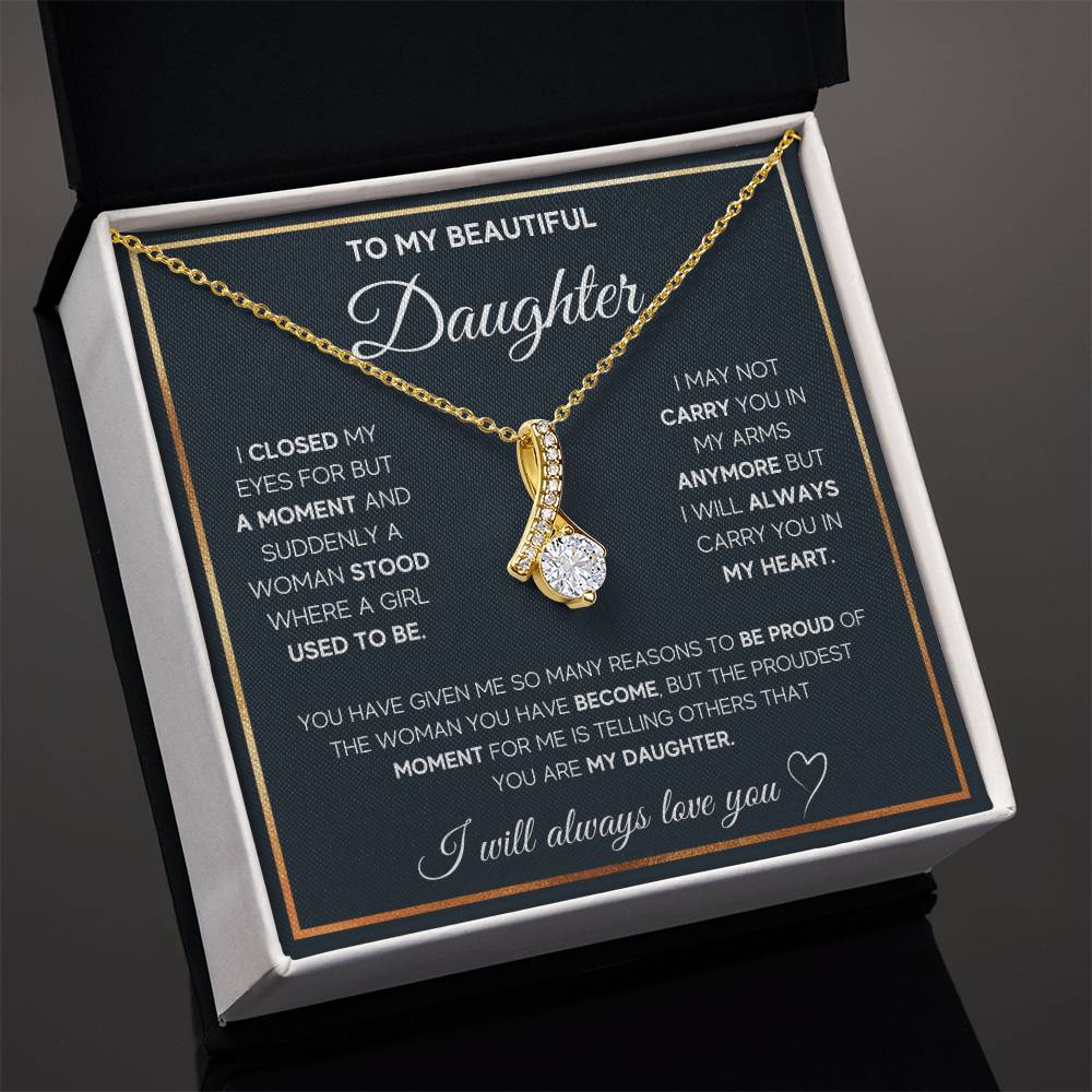 Gold-tone ribbon pendant necklace shown on a daughter message card inside an open black box