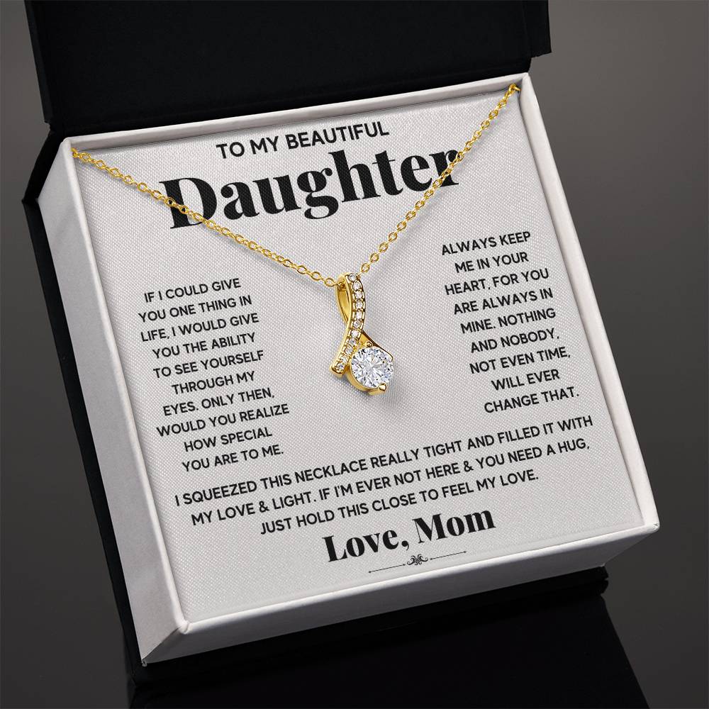 Gold ribbon pendant necklace presented in an open black jewellery box