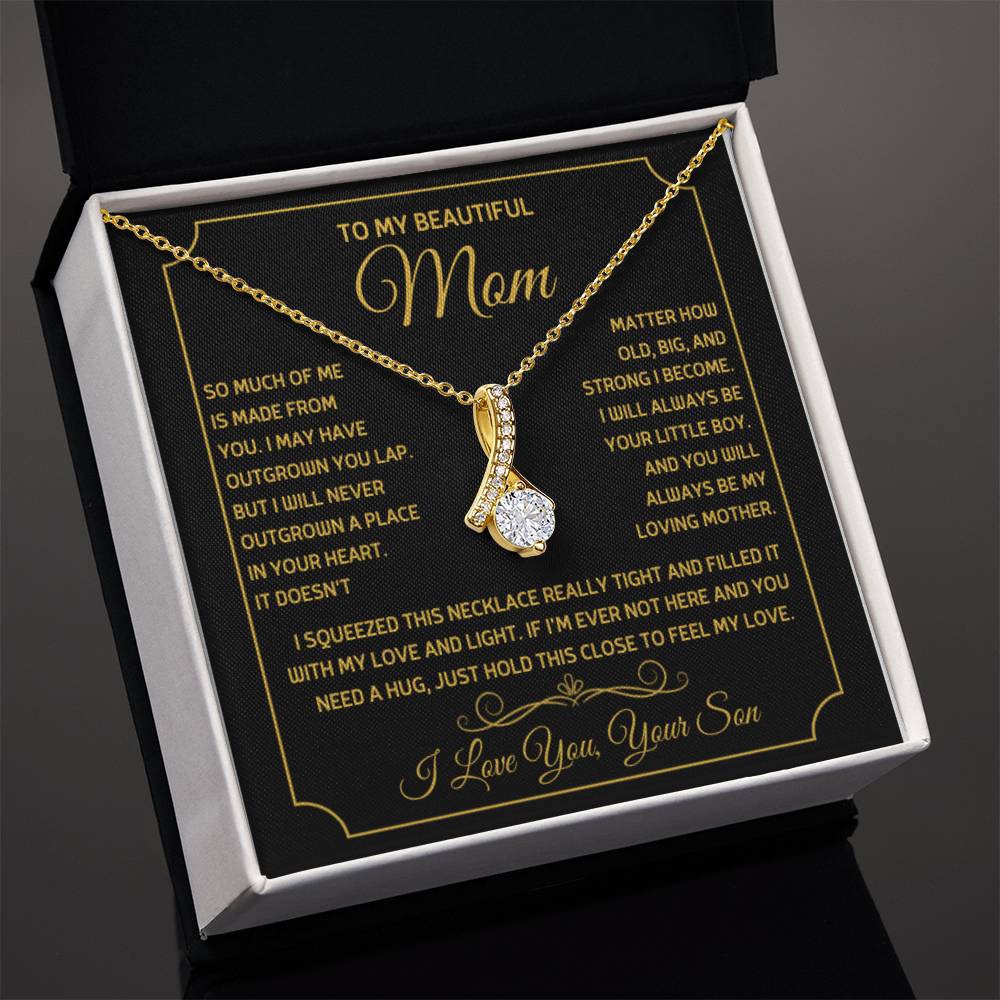 Angled view of a gold ribbon pendant necklace in an open white presentation box