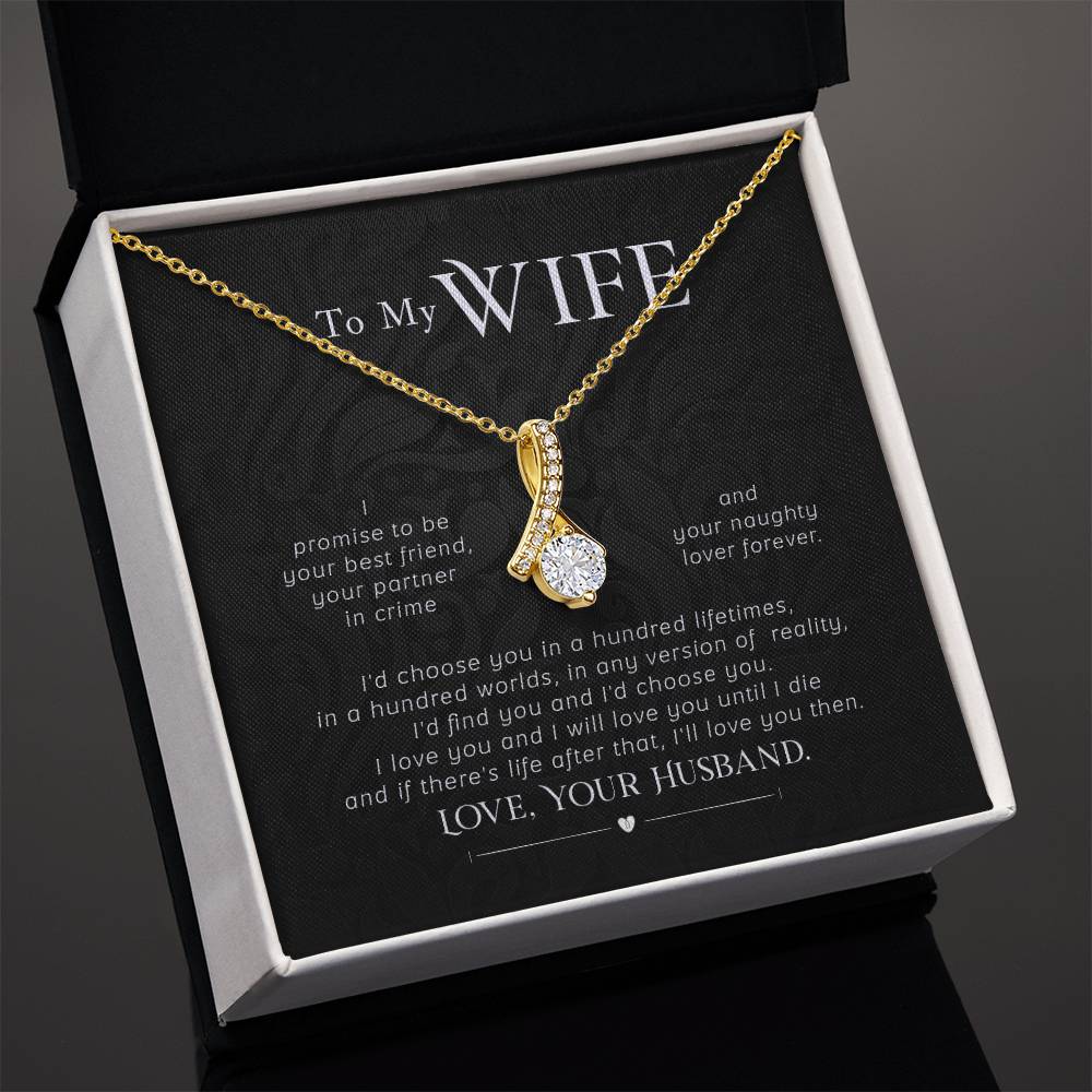 Angled view of a gold-tone ribbon pendant necklace on its printed message card.