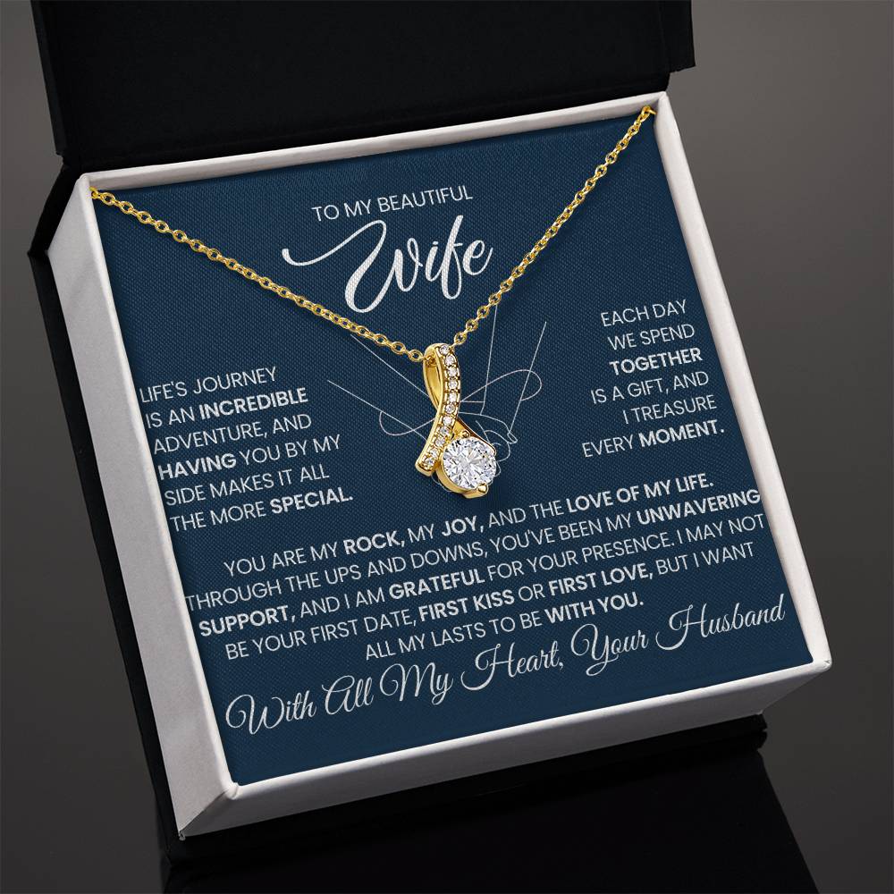 Angled open black gift box displaying a gold-tone necklace and wife message card