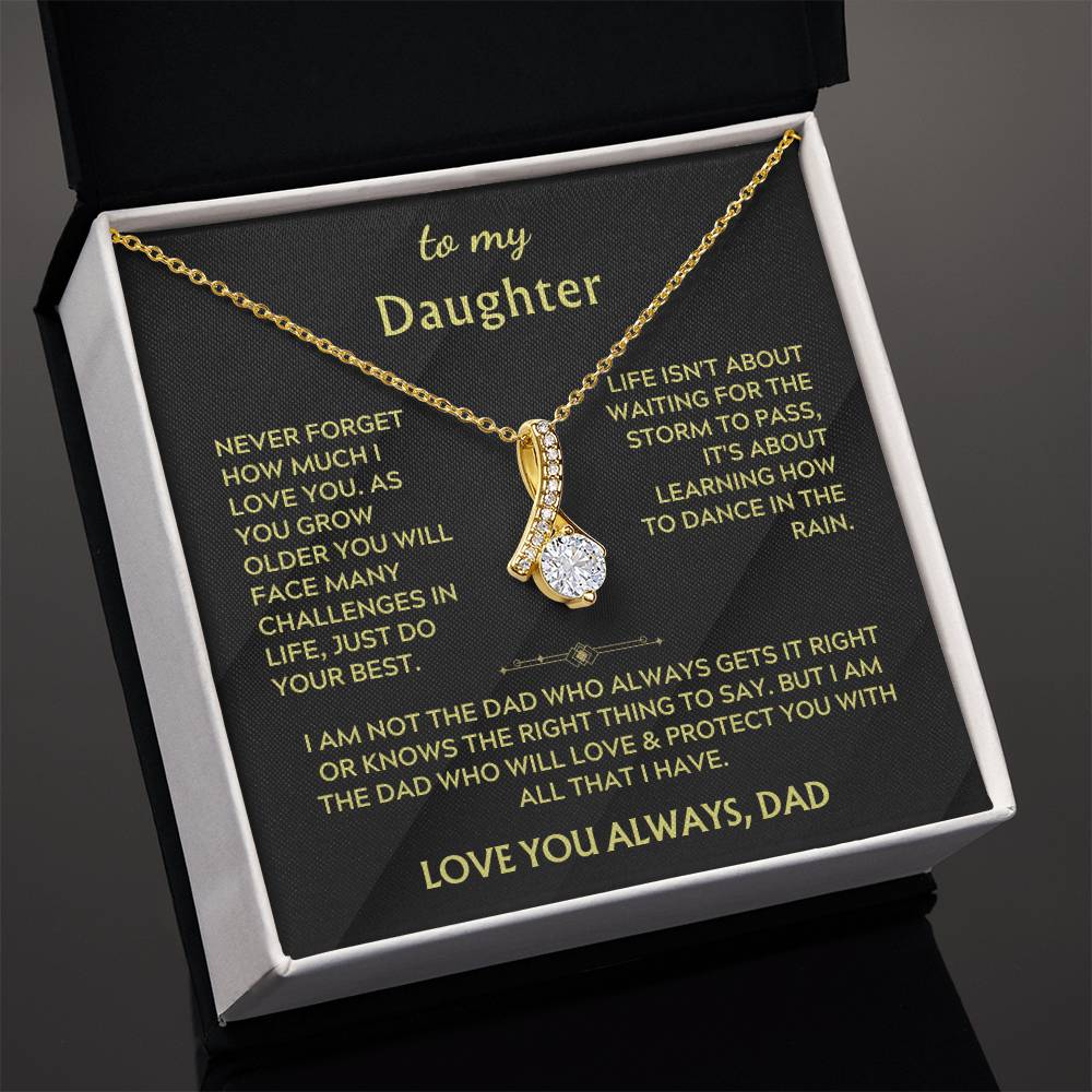 Angled open jewellery box showing a gold ribbon pendant and printed message card