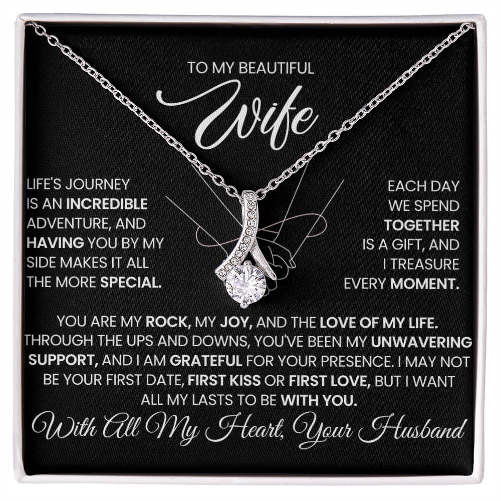 Silver-tone ribbon pendant necklace displayed on a black message card in a white box.