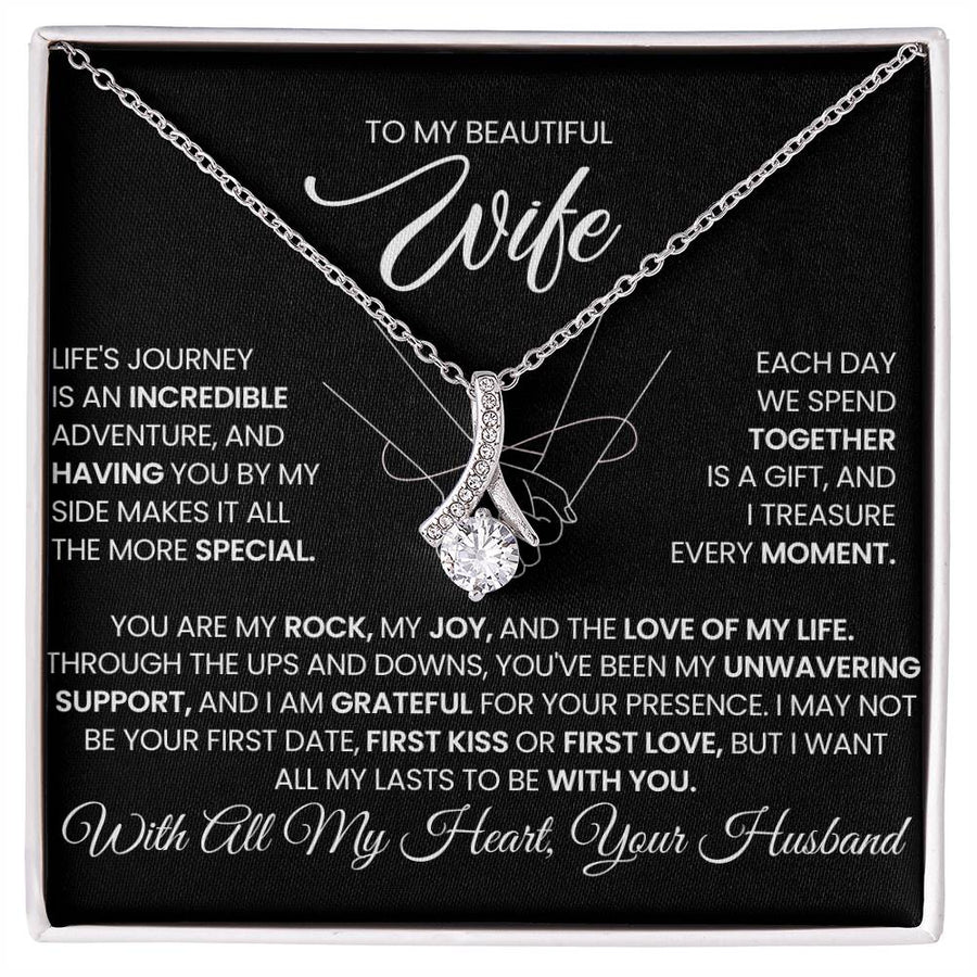 Silver-tone ribbon pendant necklace displayed on a black message card in a white box.