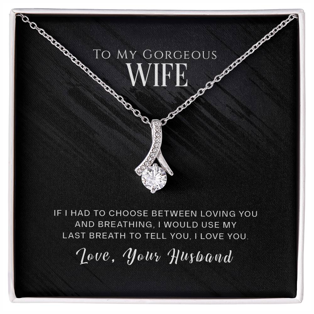 Silver-tone ribbon pendant necklace displayed on a black message card in a white box
