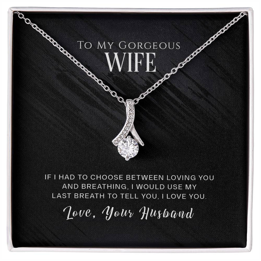 Silver-tone ribbon pendant necklace displayed on a black message card in a white box