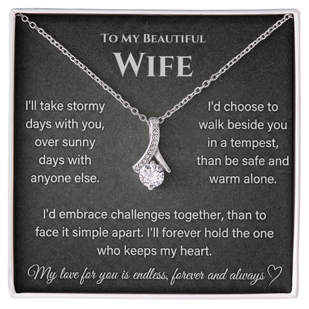 Silver-toned ribbon-shaped necklace displayed on a printed wife message card in a white-edged box.