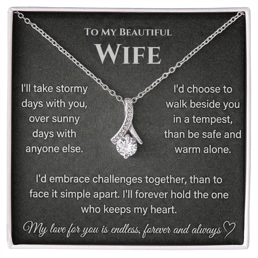 Silver-toned ribbon-shaped necklace displayed on a printed wife message card in a white-edged box.
