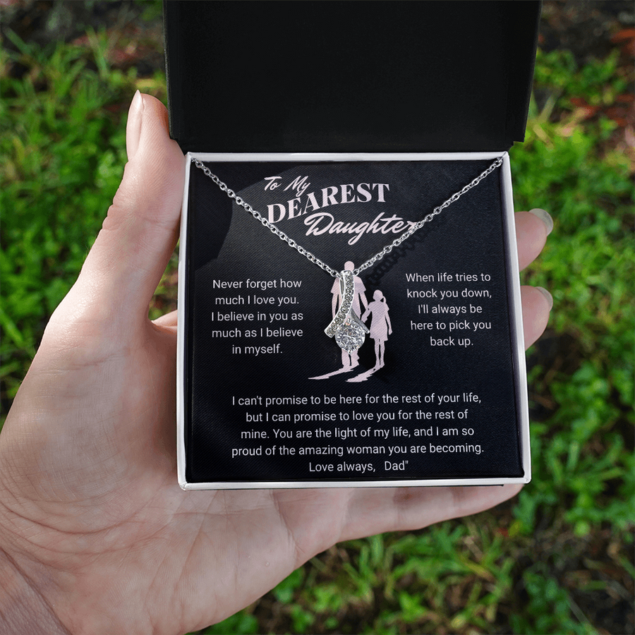 Hand holding an open jewellery box with a silver daughter message necklace outdoors