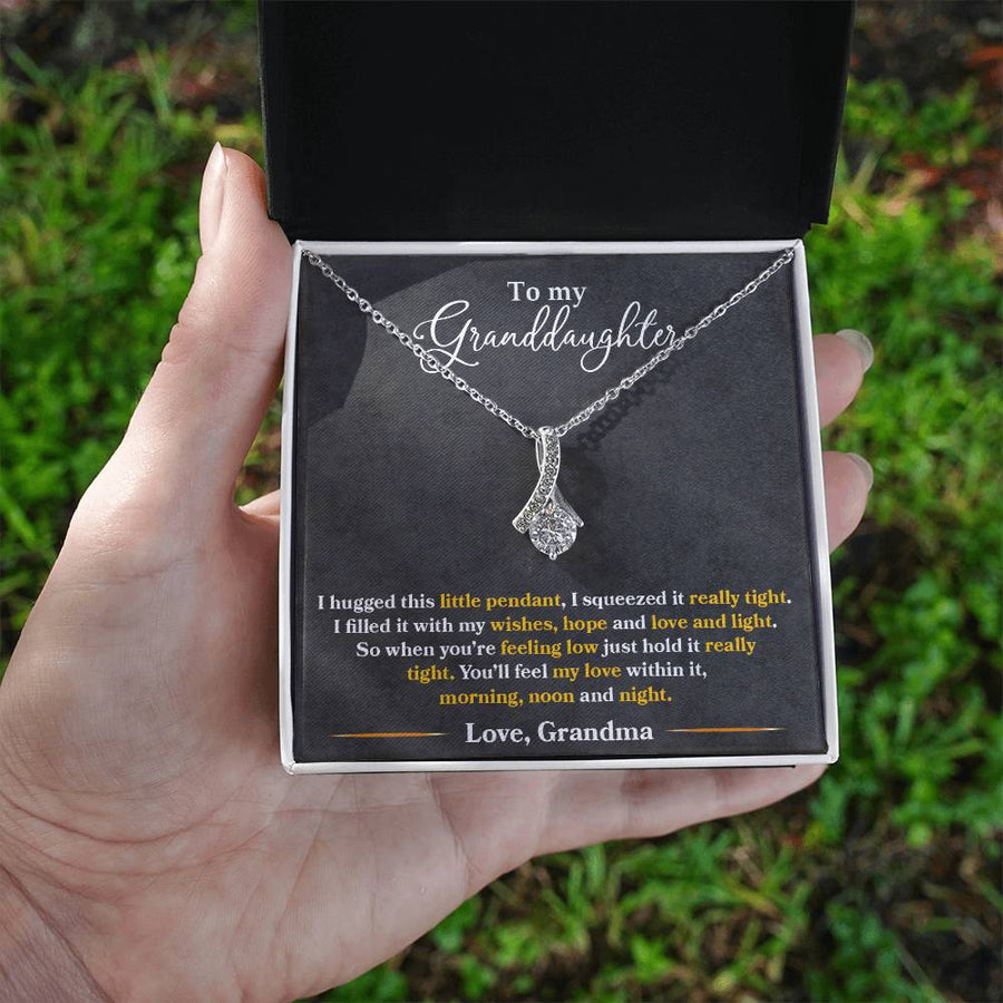 Silver granddaughter message necklace presented in an open jewellery box held outdoors