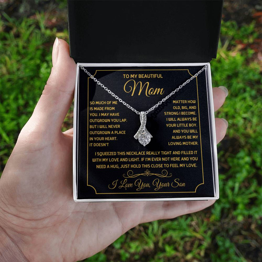 Silver ribbon pendant necklace displayed in an open white box held outdoors