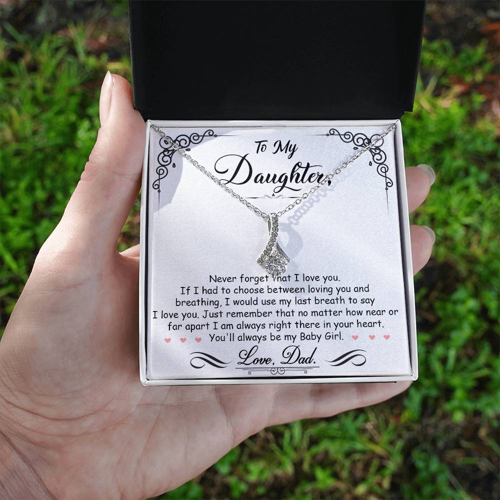 Silver daughter message necklace presented in an open box held outdoors
