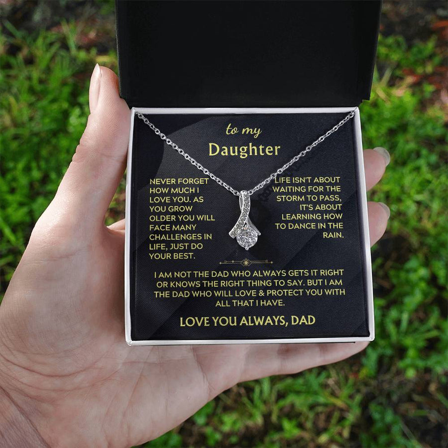 Open jewellery box with silver ribbon pendant and daughter message, held outdoors