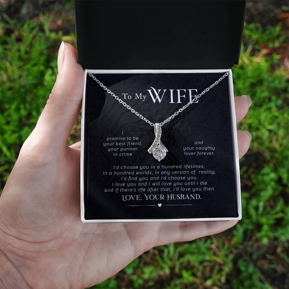 A hand holds an open jewellery box showing the wife message card and silver necklace outdoors.