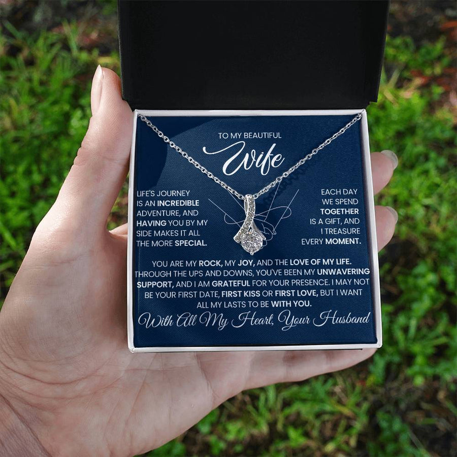 Open necklace gift box held in a hand outdoors, showing a wife message card and pendant