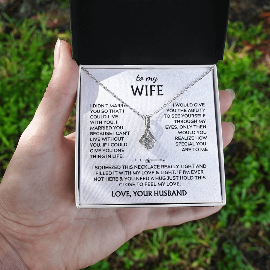 A hand holds an open jewellery box containing a silver-tone necklace and wife message card.