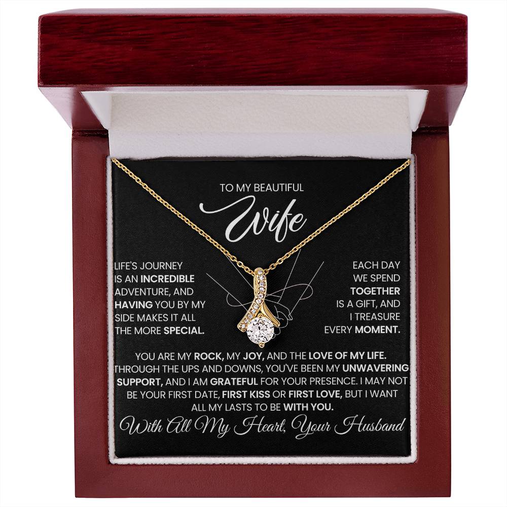 Gold-tone ribbon pendant necklace displayed in a red luxury presentation box.