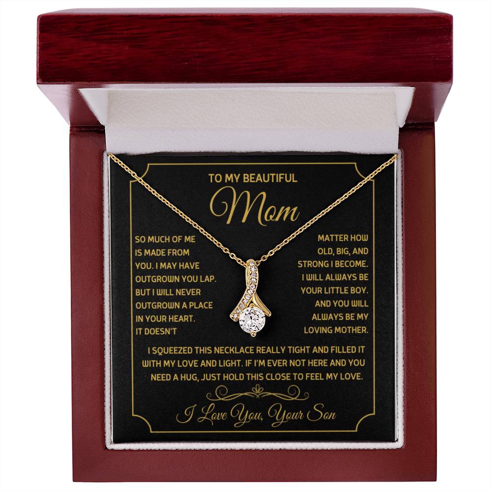 Gold ribbon pendant necklace displayed on a message card in a mahogany box