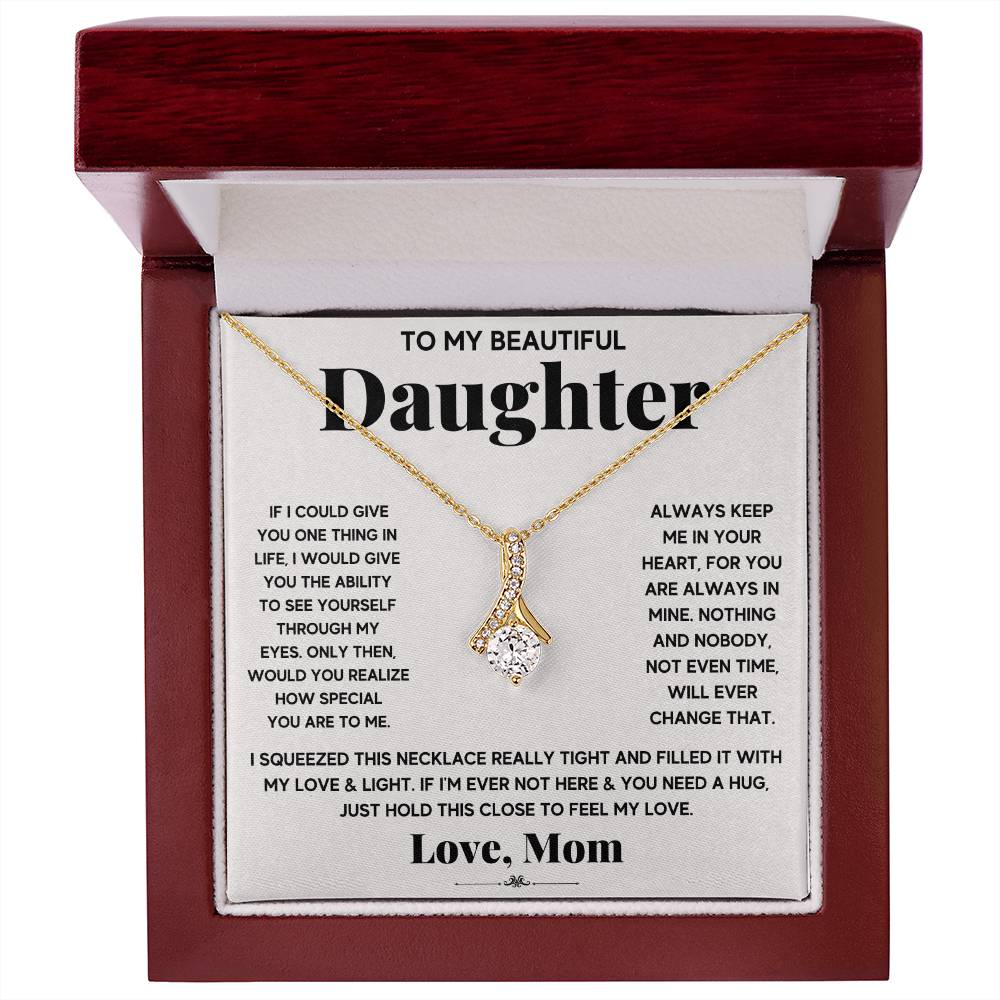 Gold ribbon pendant necklace displayed in a red wooden presentation box
