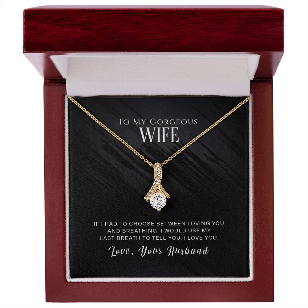 Gold-tone ribbon pendant necklace displayed in an open mahogany-style box