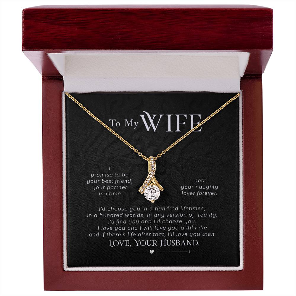 Gold-tone ribbon pendant necklace displayed in an open mahogany-style jewellery box.