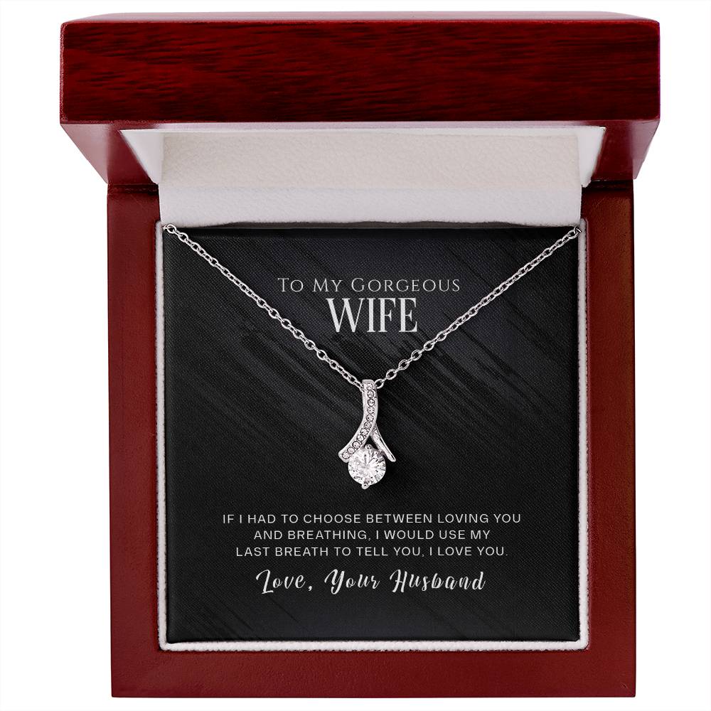 Silver-tone ribbon pendant necklace displayed in an open mahogany-style box