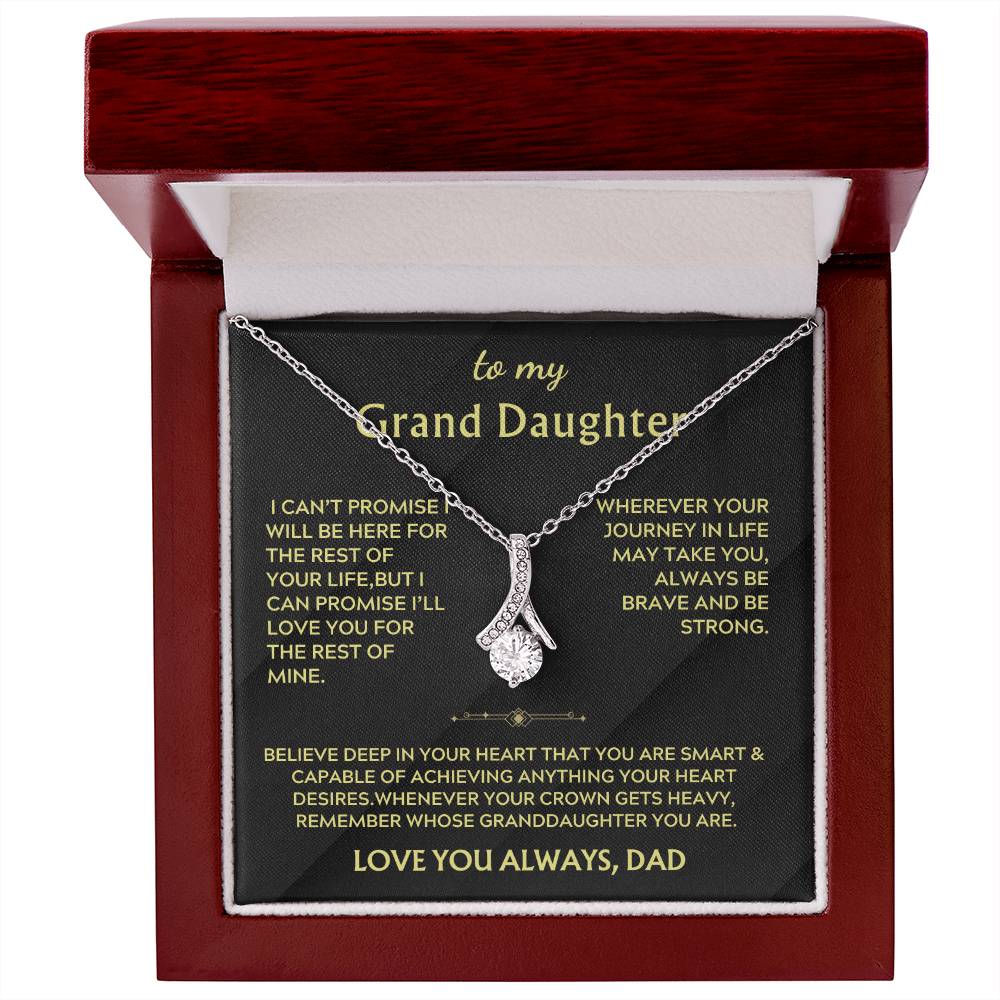 Silver ribbon pendant and message card presented inside an open mahogany-style jewellery box.