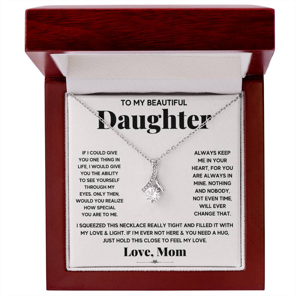Silver ribbon pendant necklace displayed in a red wooden presentation box