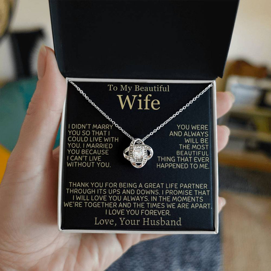 A hand holds an open jewellery box containing a silver Love Knot Necklace and wife message card
