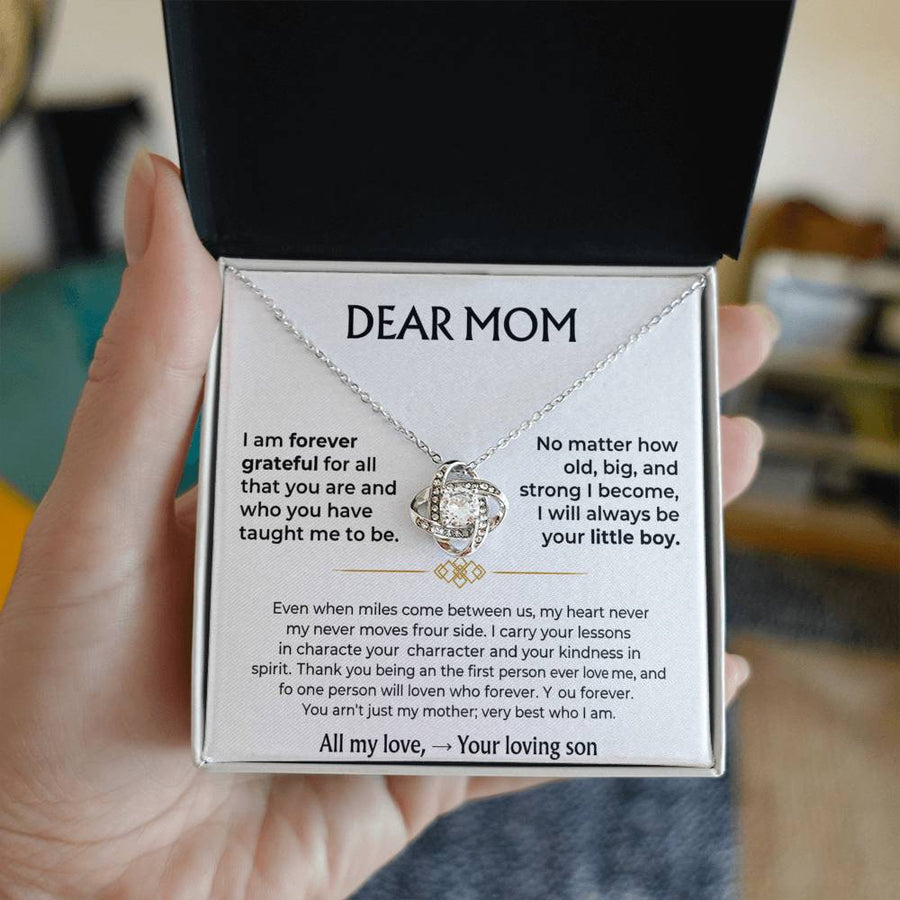Open jewellery box held in a hand, showing the Love Knot necklace and Dear Mom message card