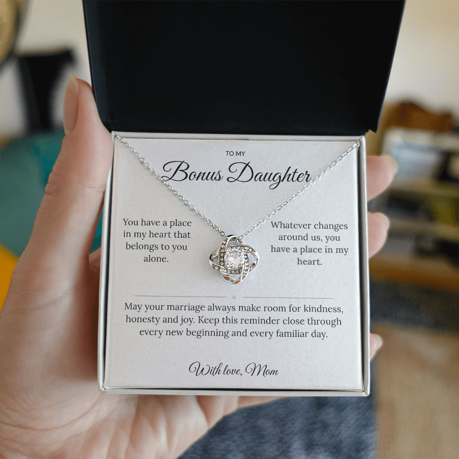 Hand holding an open jewellery box showing a Love Knot necklace and bonus daughter message card