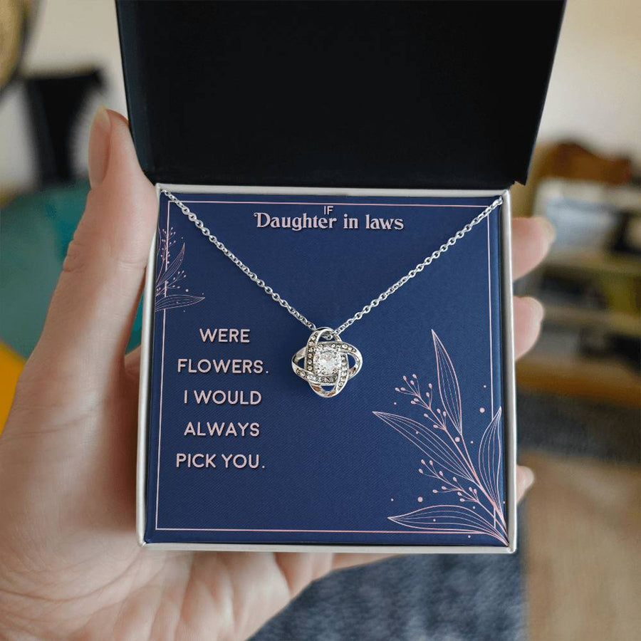 Hand holding an open jewellery box with a silver-tone necklace and blue message card