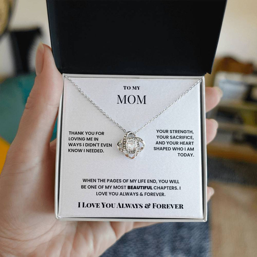 Open jewellery box held in one hand, displaying the silver Mom love knot necklace card
